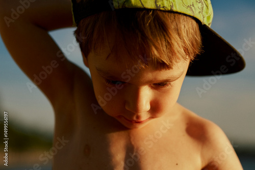 Portrait of a little cute boy in a cap by the sea in summer.