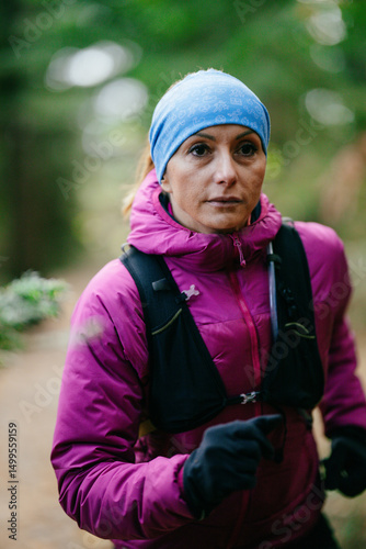 Determined Female Athlete Running with Focus Through a Dense Pine Forest, Embracing Strength and Nature