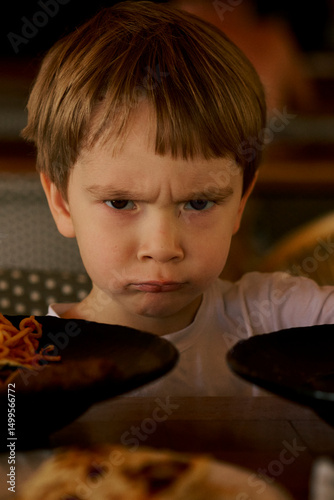 Frustrated little boy's portrait at the dinner table.