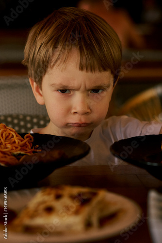 Frustrated little boy's portrait at the dinner table.