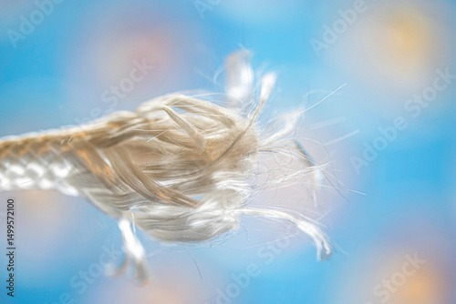 Macro of frayed end of a white nylon rope against blue background, nobody