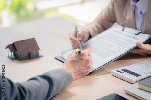 Real estate agent with documents to buy new house of house plan and keys on table. At table with model house. Real estate. Close up.