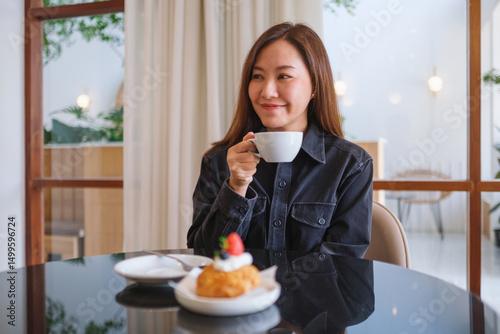Portrait image of a woman holding and drinking coffee in cafe