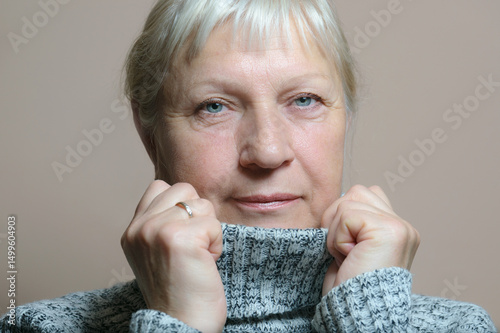 Middle aged woman portrait in sweater on beige background.