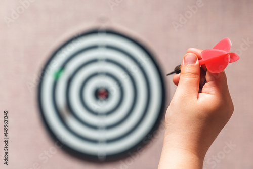 Playing darts, child's hand aiming a dart at a target