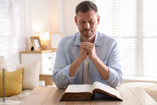 Behang Man with Bible praying at table indoors