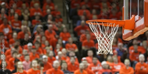 A basketball net is in the foreground of a crowd of people wearing red shirts