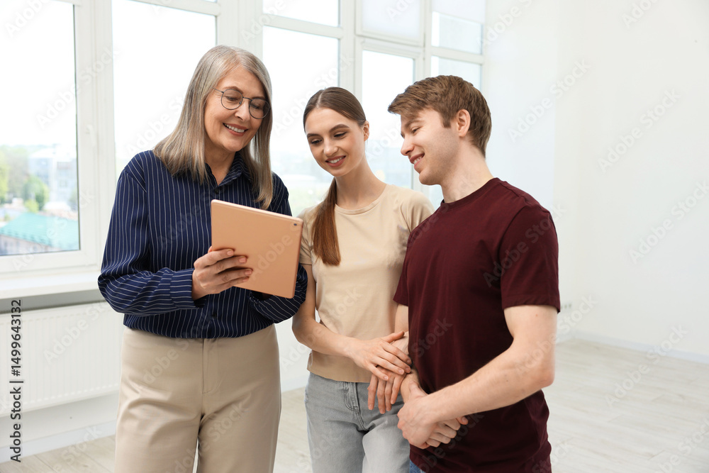 Fototapeta premium Smiling real estate agent with tablet working with couple at home
