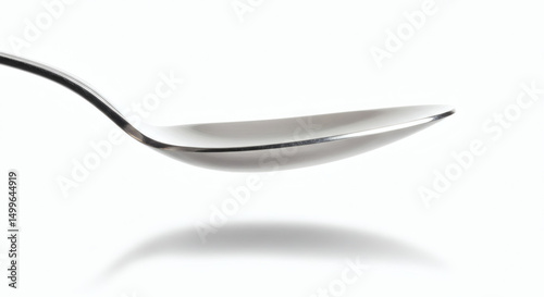 Spoon Silhouette: A sleek, stainless steel spoon, captured in a pristine studio shot, creates a minimalist composition. Its elegant curve and smooth surface suggest simplicity.