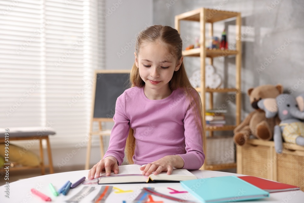 Dyslexia. Little girl reading book at table indoors Dyslexia. Little girl reading book at table indoors