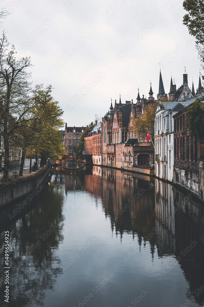 Fototapeta premium canal view at dusk in the city of brugge in belgium, with reflections on the water
