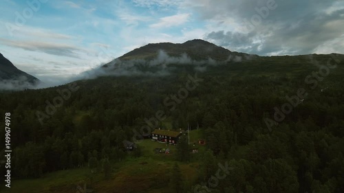 Lodge and tents in forest valley with mountain backdrop
