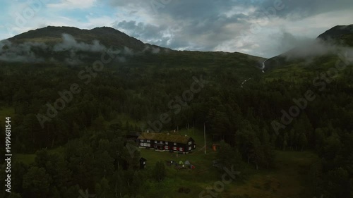 Forest clearing with wooden cabins and mountain mist