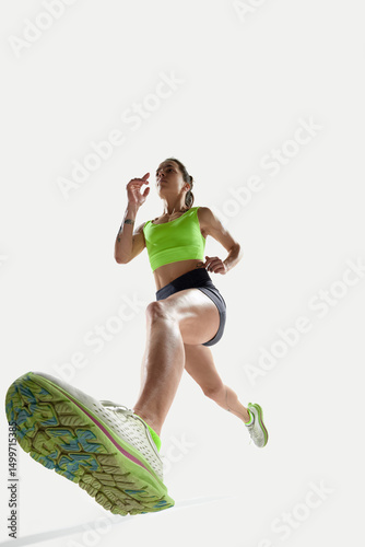 Foto Low angle shot of female runner in bright green top and black shorts, stepping forward with powerful stride