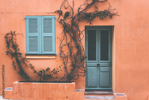 old closed window and door with green shutters on a peach colour house in saint tropez, cote d'azul