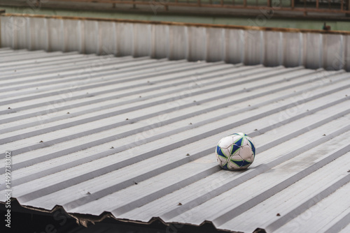 Broken football. Old soccer ball that was lost and rotted because it had been stuck on metal sheet roof for a long time background copy space.
