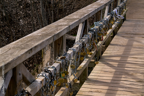 Old wooden bridge with iron locks on the fence, early spring.