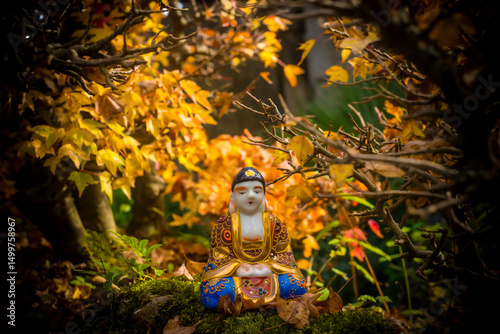 Buddha statue in a maple bonsai forest in autumn, meditation.
