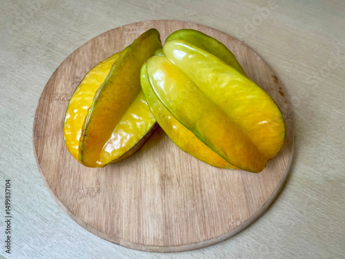Ripe star fruit on a round wooden cutting board