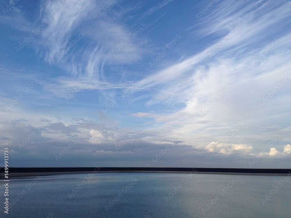 Obraz premium Sky with streaked cirrus clouds and calm water. Minimalist nature scene perfect for backgrounds, environmental themes, or designs emphasizing peace and clarity.