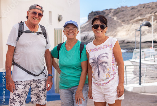 Carefree caucasian seniors friends outdoors in a sunny day looking at camera smiling. Elderly people walking visiting Europe enjoying healthy lifestyle