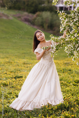 A girl in a dress and a blooming apple tree, taken at sunset