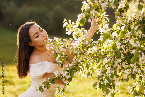 A girl in a dress and a blooming apple tree, taken at sunset