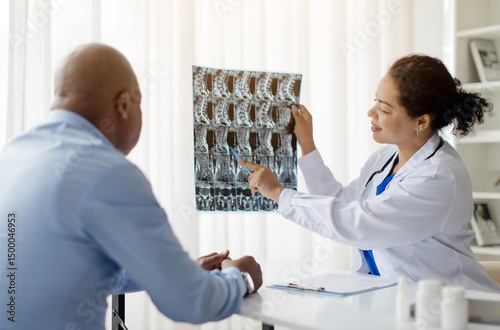 Black Doctor Woman Demonstrating Spinal X-Ray To Male Patient During Meeting In Clinic, Female Therapist In Uniform Consulting Ill Man During Appointment In Hospital, Discussing Treatment
