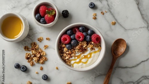 Flat lay of a healthy breakfast bowl containing granola, yogurt, fresh berries, and a drizzle of honey, placed on a marble countertop.