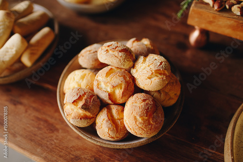 Ceramic bowl with golden cheese breads on a wooden surface. With a cracked crust and soft center, this classic from Minas Gerais represents authentic Brazilian comfort food.