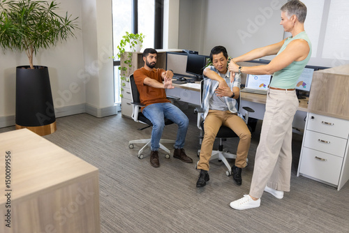 Stretching Diverse coworkers doing arm stretches in modern office, with swivel chairs and monitors