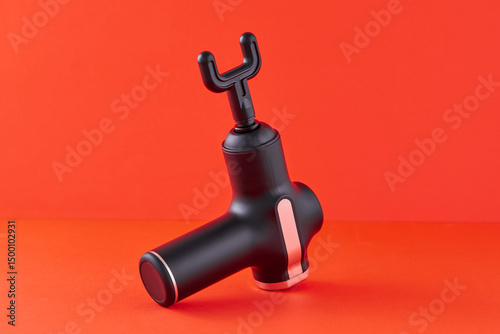 Massage gun for body massage isolated on orange background. Machine for body massage or shock vibration massager. Tool for Self Massage.