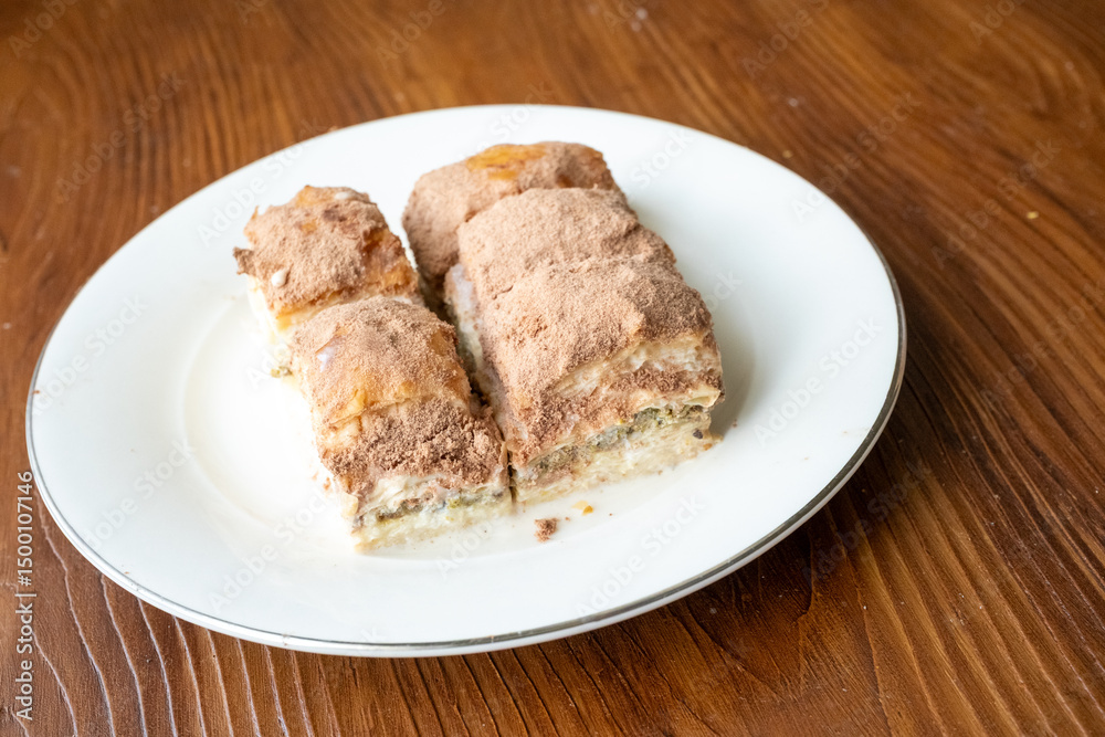 Cold baklava with cacao on a white plate close up Cold baklava with cacao on a white plate close up