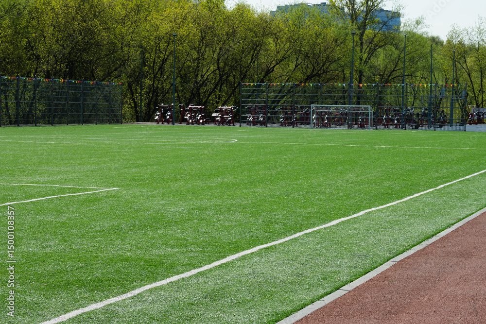 Obraz premium Soccer goal on big field with artificial green grass. Outdoor sports activities. Sports ground, field with artificial turf for playing soccer and other ball sport games. Summer season.