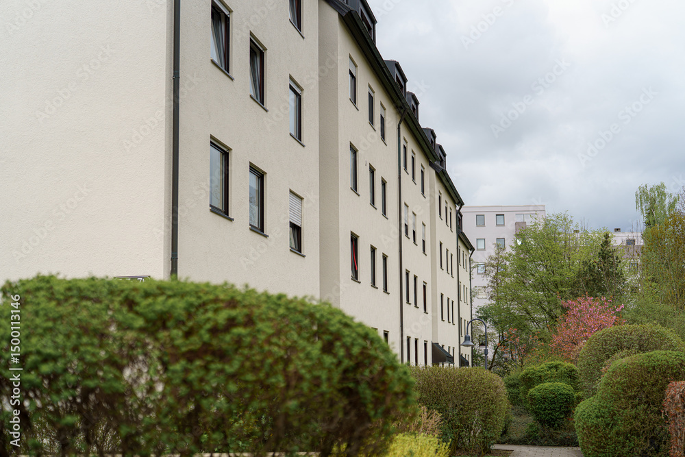 Fototapeta premium Modern residential building surrounded by greenery in a quiet urban neighborhood on an overcast day