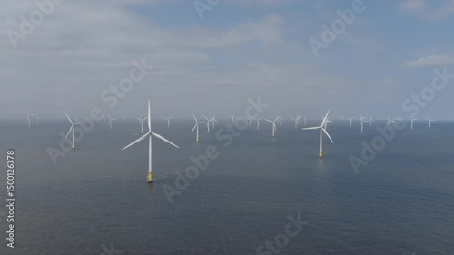 Aerial view of large offshore wind farm in the United Kingdom. Wind turbines generating green energy towards the energy transition.