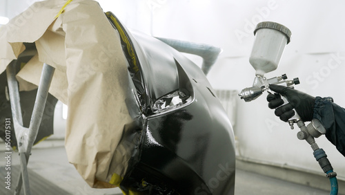 Tableau sur toile Mechanic painting car bumper in auto repair shop
