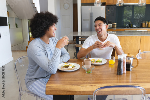 Sharing breakfast diverse male friends sitting at table in kitchen, with avocado toast and coffee photo