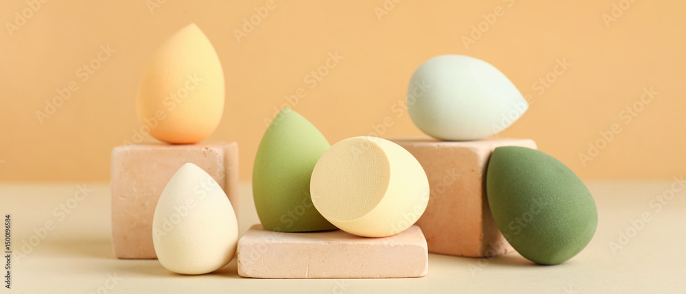 Fototapeta premium Decorative podiums with makeup sponges on beige background
