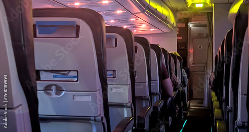Airplane inside at night. Empty passengers seats in the dark. Travel the world concept.