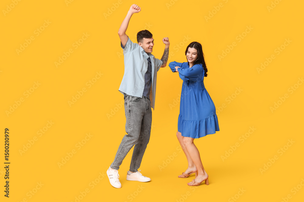 Fototapeta premium Happy young couple dancing on yellow background