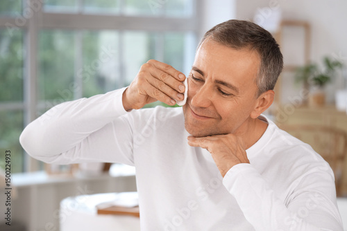 Mature man cleansing face w...