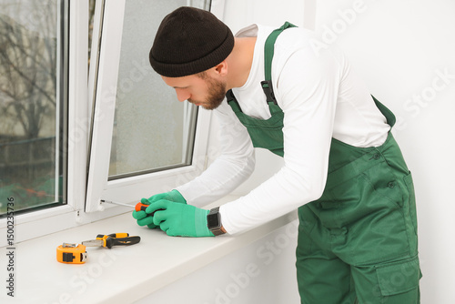 Male worker screwing window...