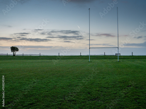 Silhouette of a tall goal posts in a field against dramatic sunrise sky. National sport of Ireland equipment. Rugby, camogie, hurling training ground. Calm and relaxing mood.