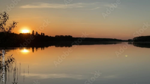 Sunset over calm lake with reflection and scenic landscape in serene evening