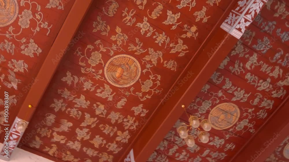 A red color intricately decorated with traditional Thai style floral patterns ceiling of Wat Mai Chai Wichit Buddhist temple in Ayutthaya, Thailand