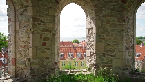 A hyperrealistic shot from the perspective of looking out through an arched window of one of Visby's iconic medieval church ruins