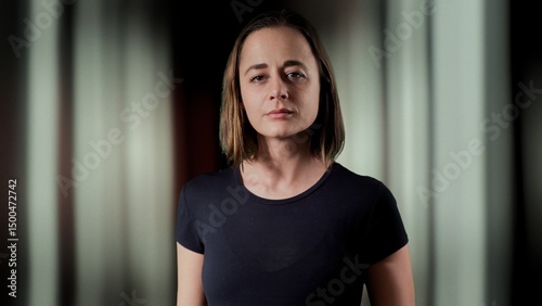 Serious businesswoman posing in a dark room with striped background