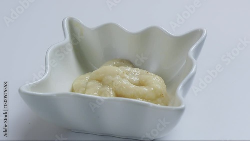 Horseradish grated spicy homemade seasoning in a gravy boat rotates in a circle. Medium shot.