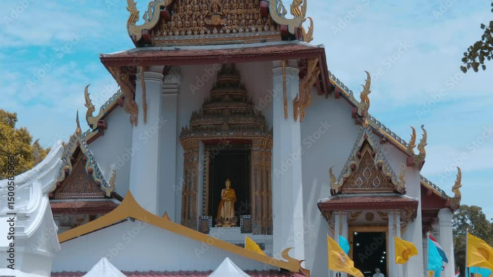 Facade of amazingly beautiful Wat Na Phra Meru Rachikaram Buddhist temple with doors and gold carved roofs and doors with a golden statue of standing Buddha